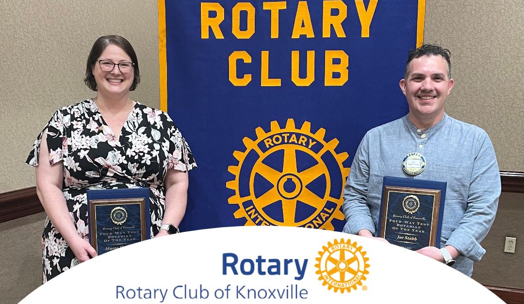 Margo Hughes and Joe Stabb standing in front of the Rotary banner holding their awards.